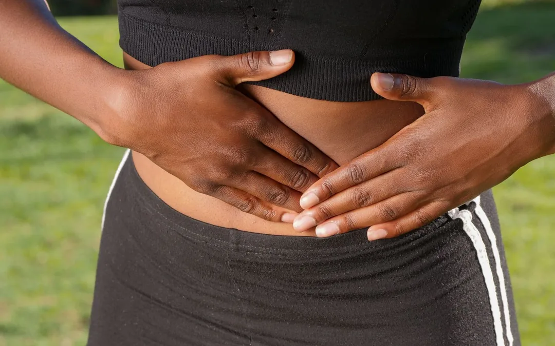 A person outdoors holding their stomach in discomfort