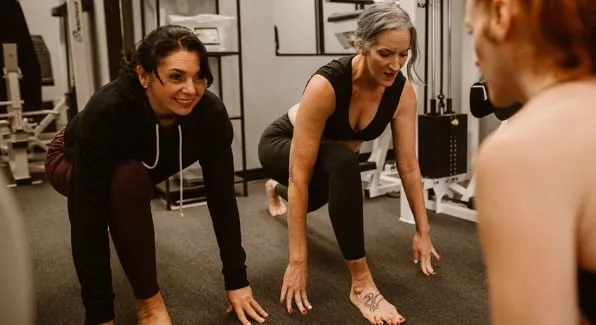 Women in a gym stretching at the start of an exercise class