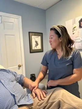 A practitioner treating a patient lying on a treatment table in the clinic