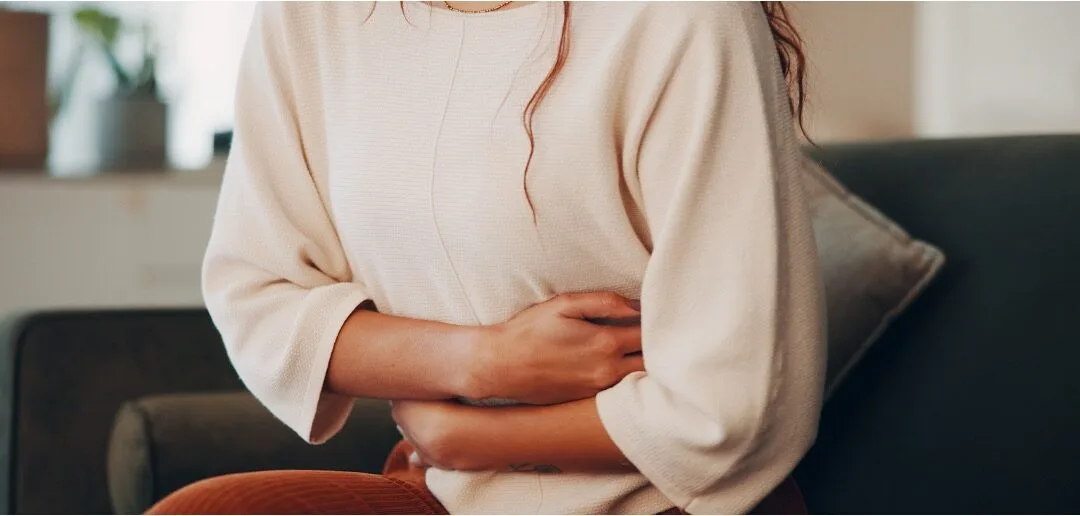 A woman sitting on a sofa with both arms wrapped around her middle